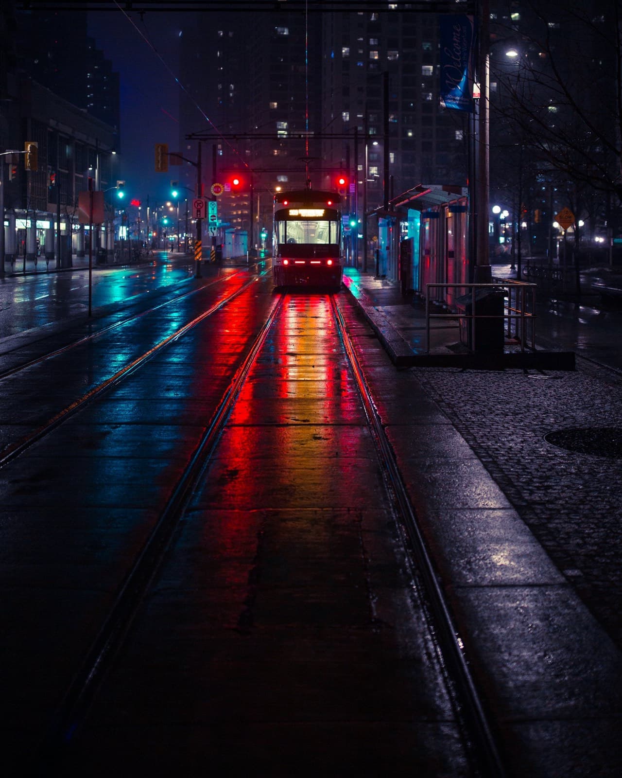 A tram stop on a rainy city street at night